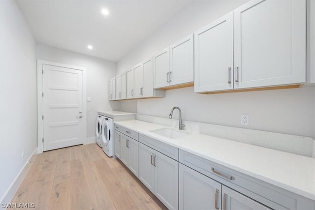 23517 Coconut Landing Dr, Estero, FL 34134 - washroom featuring light wood finished floors, cabinet space, a sink, separate washer and dryer, and baseboards
