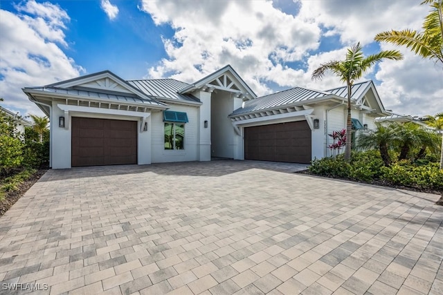 view of front of home with decorative driveway, a standing seam roof, and an attached garage