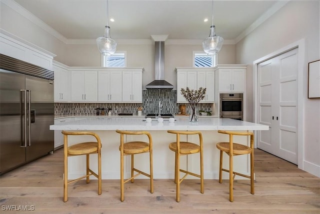 23517 Coconut Landing Dr, Estero, FL 34134 - kitchen with stainless steel built in refrigerator, crown molding, light countertops, wall chimney range hood, and backsplash