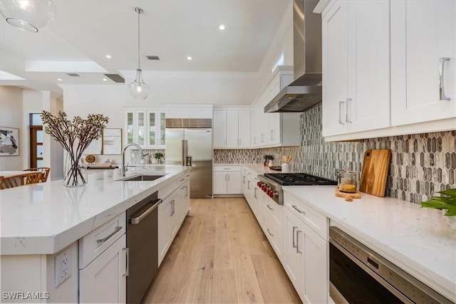 23517 Coconut Landing Dr, Estero, FL 34134 - kitchen with tasteful backsplash, white cabinets, a sink, built in appliances, and wall chimney exhaust hood