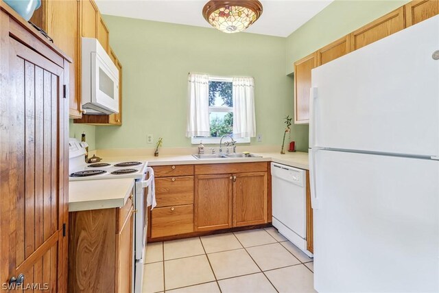 kitchen featuring light tile patterned flooring, white appliances, and sink