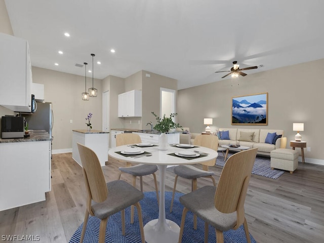 dining area with light hardwood / wood-style floors, ceiling fan, and sink