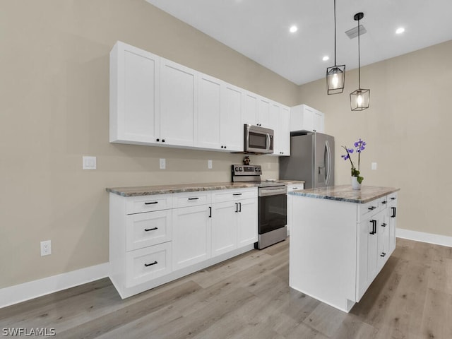 kitchen featuring decorative light fixtures, a kitchen island, white cabinetry, and stainless steel appliances