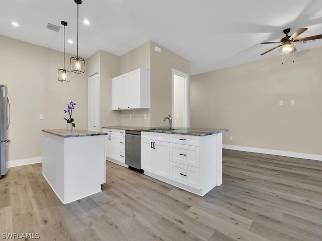 kitchen with white cabinets, pendant lighting, dark stone counters, and an island with sink