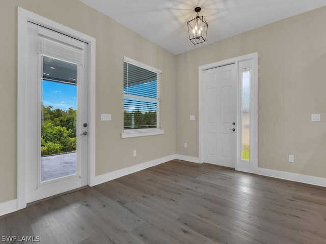 foyer entrance with a wealth of natural light, hardwood / wood-style floors, and a notable chandelier