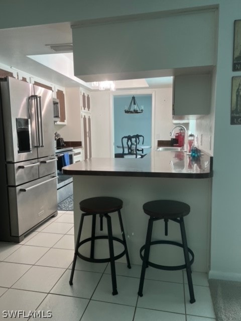 kitchen with high end refrigerator, sink, light tile floors, and kitchen peninsula