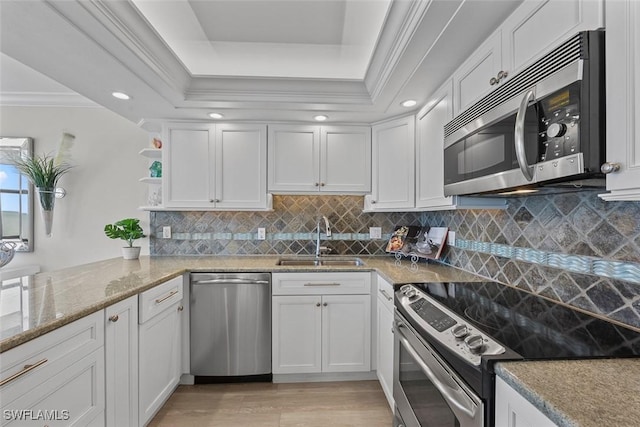 kitchen featuring appliances with stainless steel finishes, sink, white cabinets, and a tray ceiling