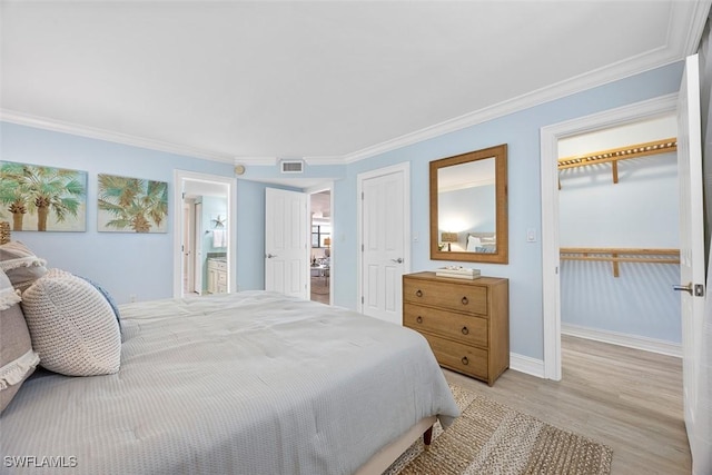 bedroom with light hardwood / wood-style floors, ensuite bath, and crown molding