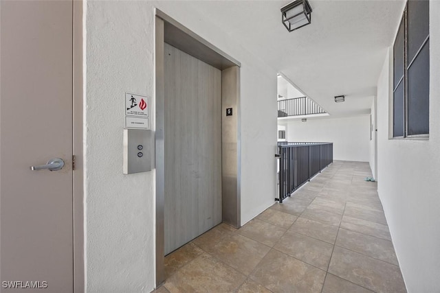 hall with elevator and light tile patterned floors