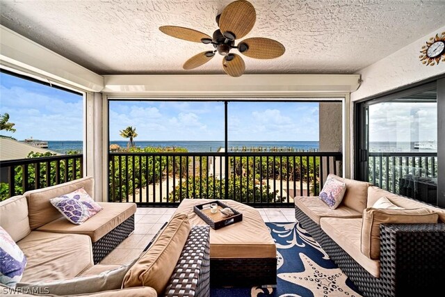 sunroom with ceiling fan and a water view