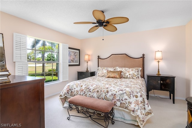 bedroom featuring a textured ceiling, ceiling fan, and light carpet