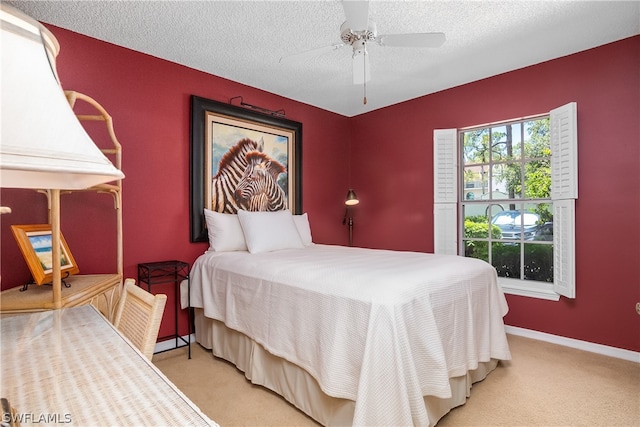 bedroom with ceiling fan, light carpet, and a textured ceiling