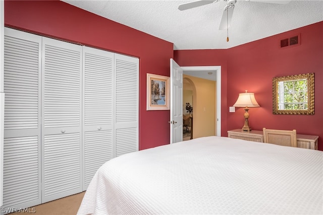 bedroom with carpet flooring, ceiling fan, a closet, and a textured ceiling