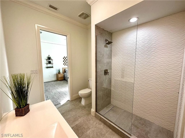 bathroom featuring a tile shower, vanity, toilet, and crown molding