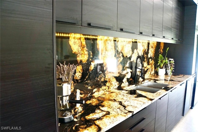 interior details featuring gray cabinetry, light stone counters, and sink