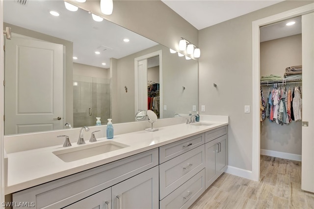 bathroom with hardwood / wood-style floors, vanity, and an enclosed shower