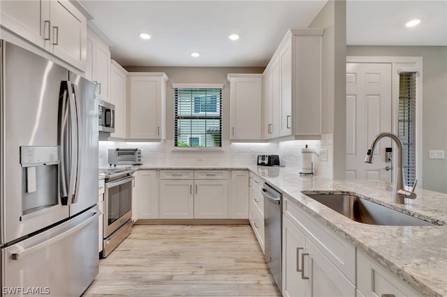 kitchen with white cabinetry, sink, light hardwood / wood-style flooring, and appliances with stainless steel finishes