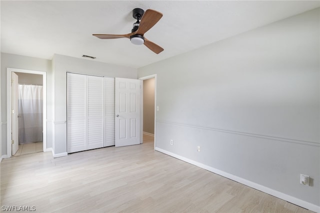 unfurnished bedroom featuring ceiling fan, light hardwood / wood-style floors, ensuite bathroom, and a closet