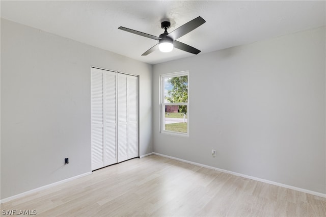 unfurnished bedroom featuring ceiling fan, light wood-type flooring, and a closet