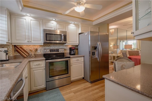 kitchen with white cabinets, ornamental molding, tasteful backsplash, light hardwood / wood-style floors, and stainless steel appliances