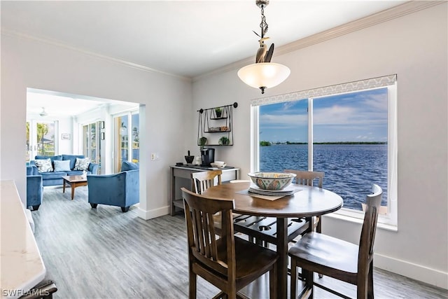 dining area with a water view, crown molding, and hardwood / wood-style floors