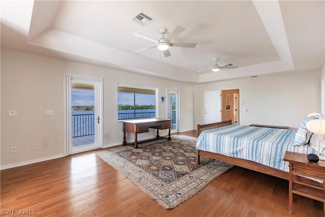 bedroom featuring hardwood / wood-style flooring, ceiling fan, a raised ceiling, and access to outside