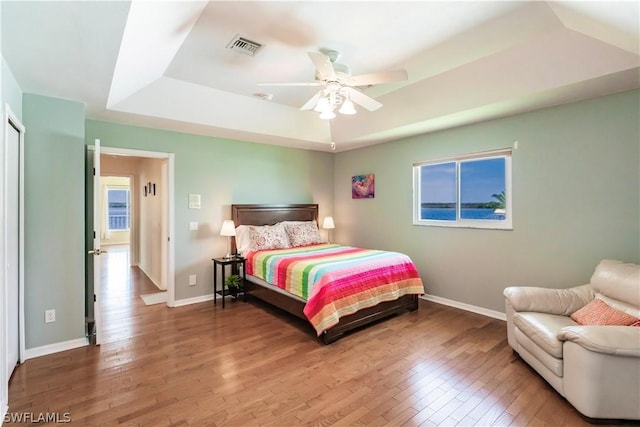 bedroom featuring ceiling fan, a tray ceiling, and hardwood / wood-style floors