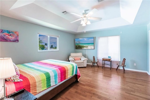 bedroom featuring a raised ceiling, ceiling fan, and wood-type flooring