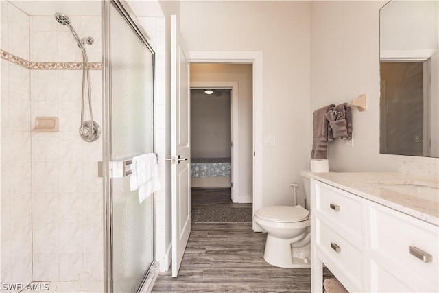 bathroom featuring toilet, vanity, wood-type flooring, and a shower with shower door