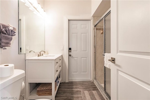 bathroom with a shower with shower door, hardwood / wood-style floors, toilet, and vanity