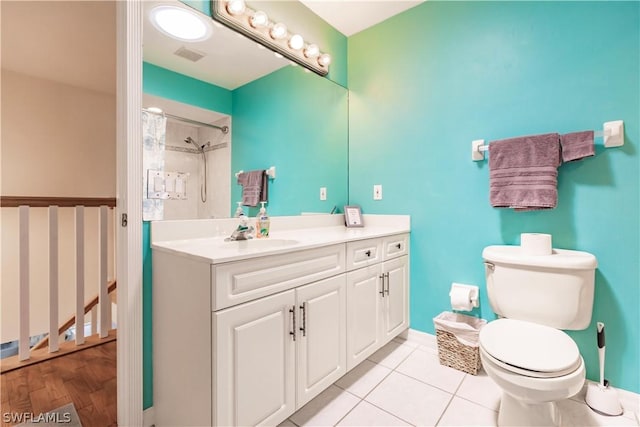 bathroom with toilet, vanity, tile patterned floors, and a tile shower