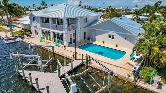 rear view of house featuring a water view, a balcony, and a patio