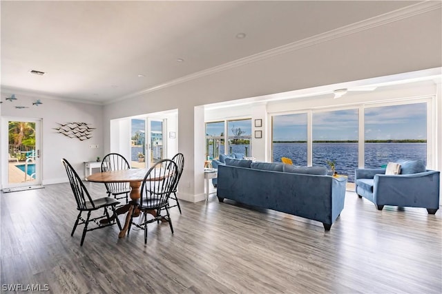 dining area with a water view, wood-type flooring, and ornamental molding