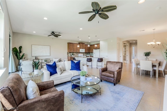 living room with light tile patterned floors and ceiling fan with notable chandelier