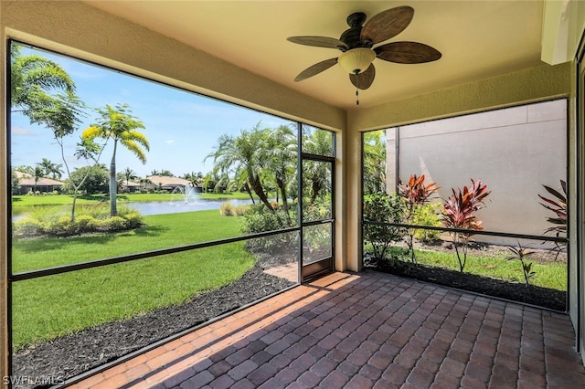 unfurnished sunroom with a water view and ceiling fan