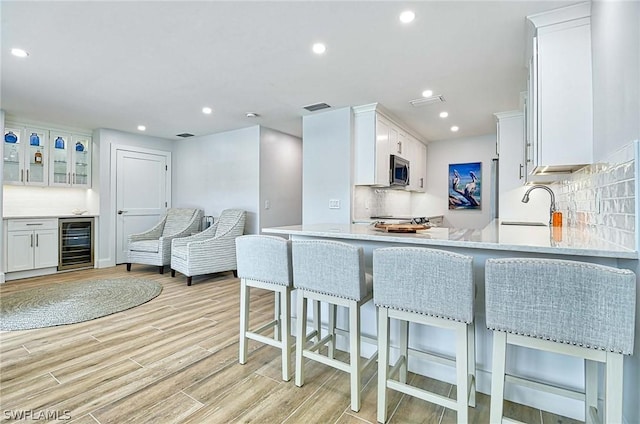 kitchen featuring white cabinets, backsplash, wine cooler, and sink