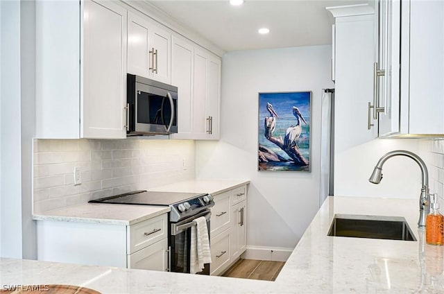 kitchen with light stone counters, sink, white cabinets, and appliances with stainless steel finishes