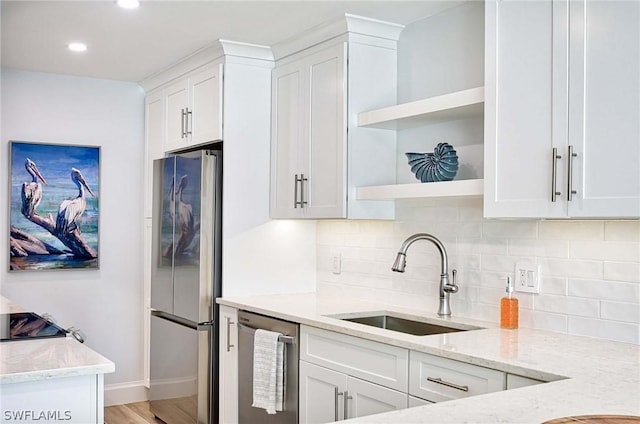 kitchen with white cabinets, appliances with stainless steel finishes, light stone countertops, and sink