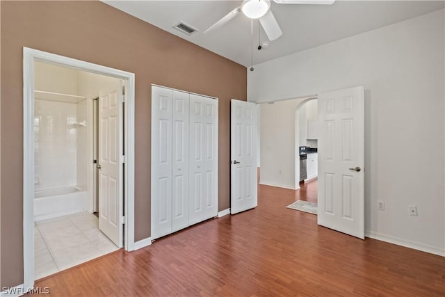 unfurnished bedroom with ensuite bath, a closet, ceiling fan, and light wood-type flooring