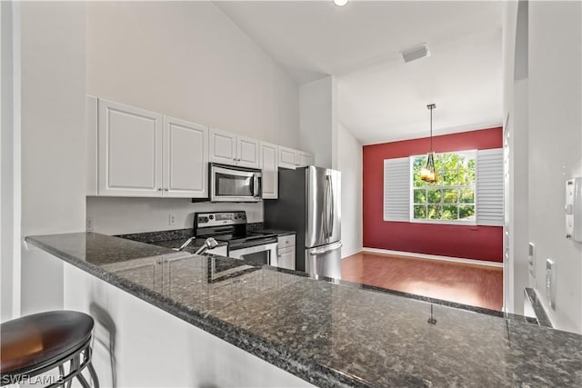 kitchen with hanging light fixtures, kitchen peninsula, white cabinets, and appliances with stainless steel finishes