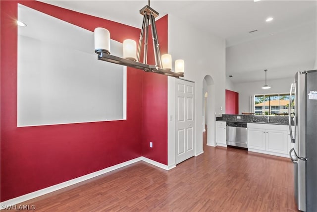 kitchen with sink, appliances with stainless steel finishes, dark hardwood / wood-style floors, kitchen peninsula, and white cabinets