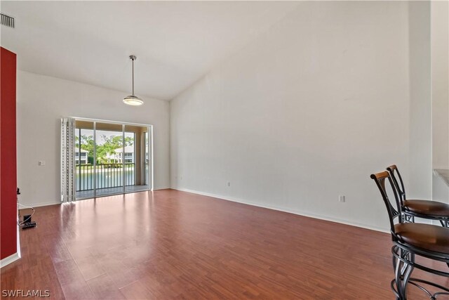 unfurnished dining area featuring dark hardwood / wood-style floors and high vaulted ceiling