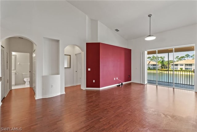 unfurnished living room featuring high vaulted ceiling and dark hardwood / wood-style floors