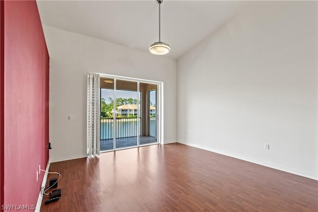 spare room with dark hardwood / wood-style flooring and vaulted ceiling