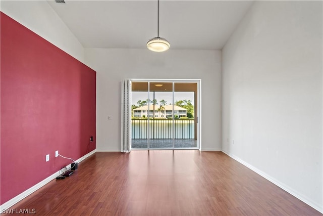 empty room with hardwood / wood-style floors and a water view