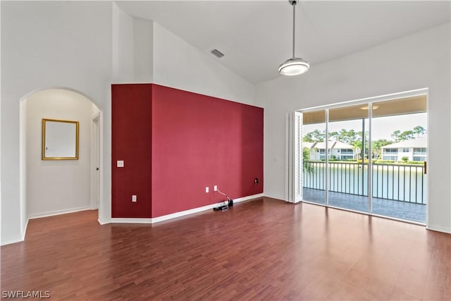 empty room featuring dark wood-type flooring and high vaulted ceiling