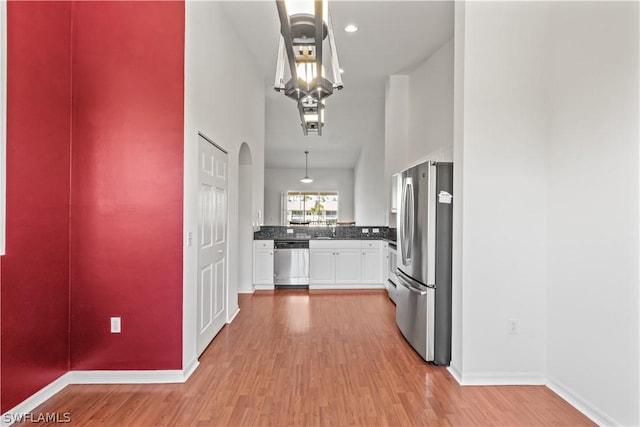 kitchen with stainless steel appliances, sink, white cabinets, and light hardwood / wood-style floors