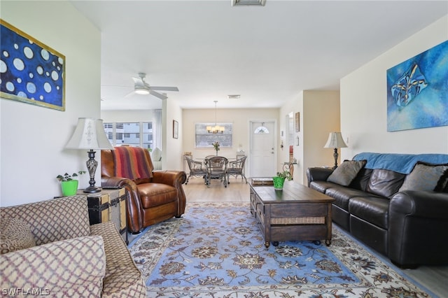 living room featuring ceiling fan with notable chandelier and light hardwood / wood-style floors