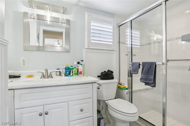 bathroom featuring toilet, a shower with shower door, and vanity