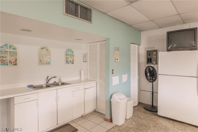 kitchen with white fridge, white cabinetry, a paneled ceiling, electric panel, and sink